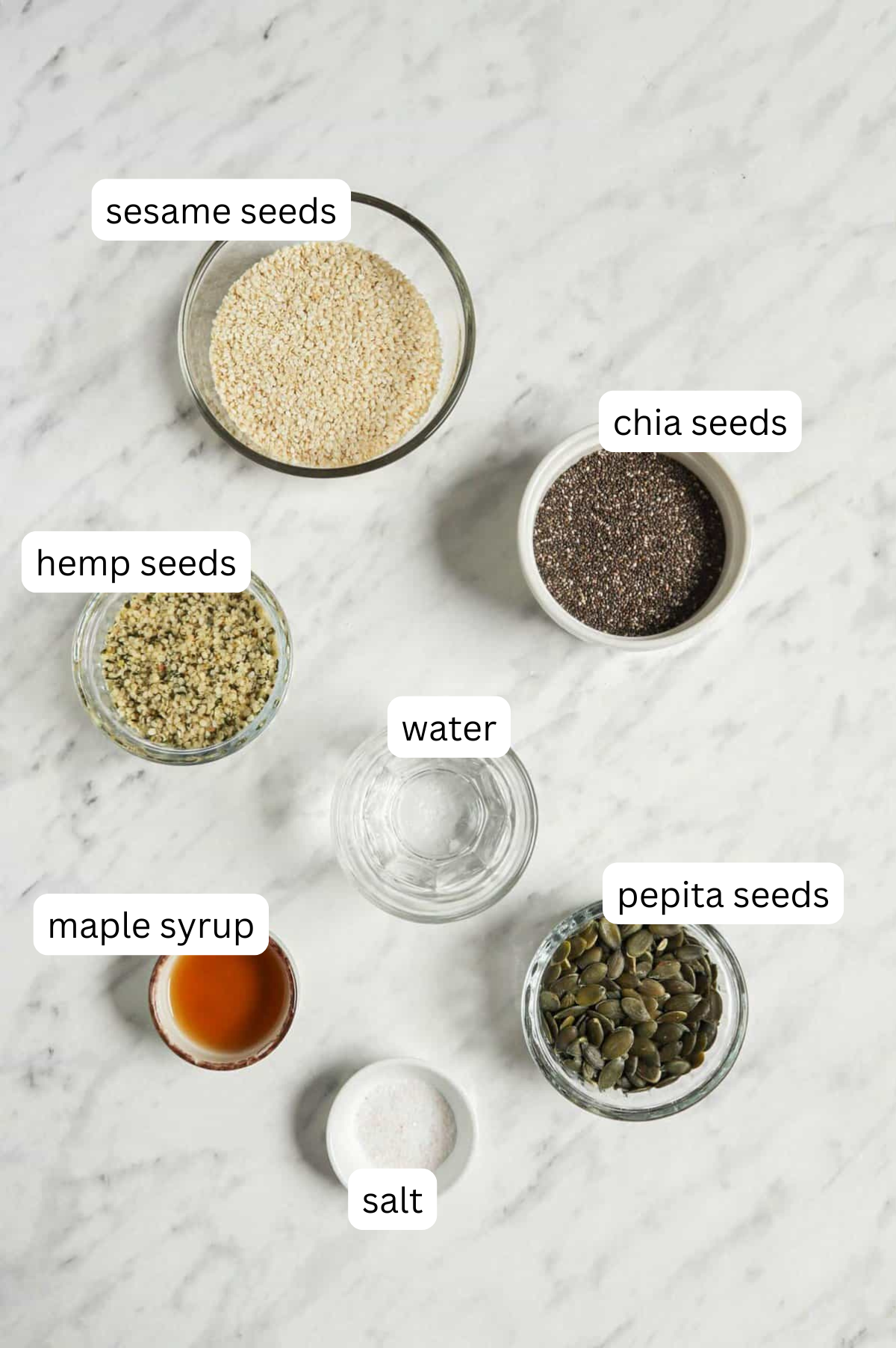Ingredients of gluten-free crackers with a white marble background.