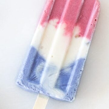 Dye-free red, white and blue popsicle with a wooden stick and a white background.
