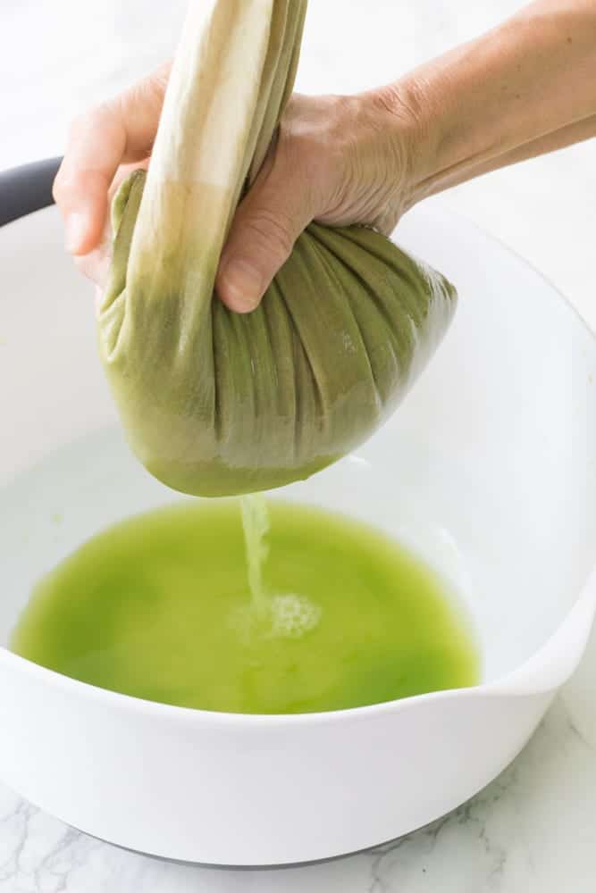 hand pushing juice out of the nut milk bag 