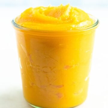 Homemade pumpkin purée in a glass jar with a white background.