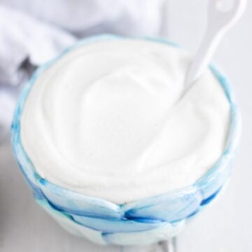 Vegan cashew cream in a blue bowl with a white background.