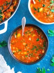 Vegan minestrone soup in a black bowl with a blue background.