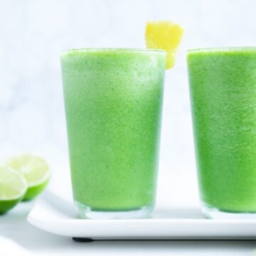 Green detox smoothies in glass cups with a white background.