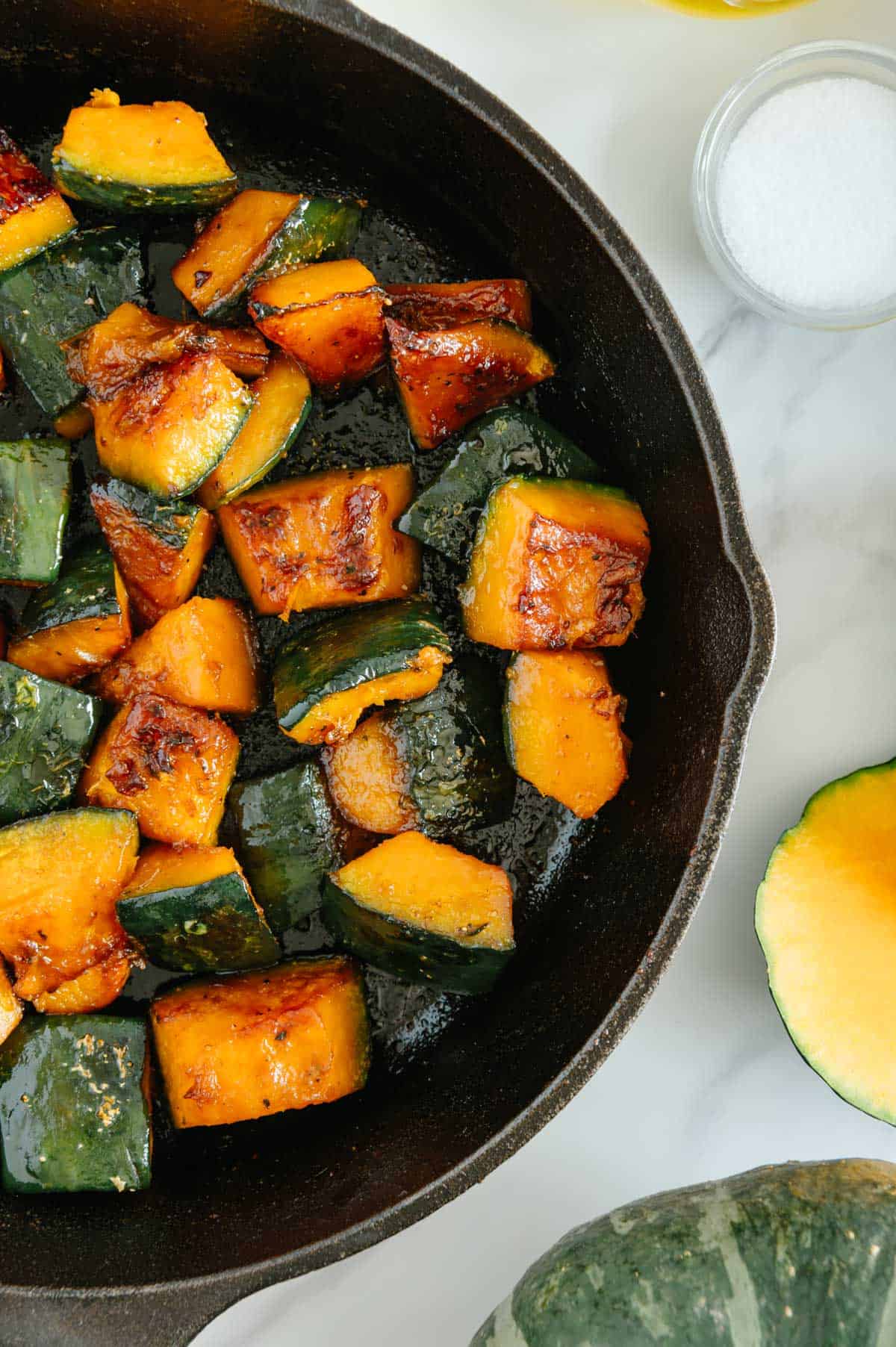 Roasted Kabocha Squash in a cast iron skillet with a white background.