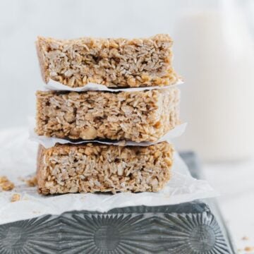 Three vegan oat bars stacked on top of each other with parchment paper in between each.