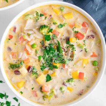 Vegetable orzo soup in a white bowl served with crusty bread.