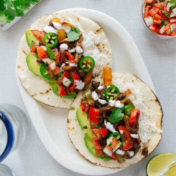 Two vegan fajitas served on a white plate.