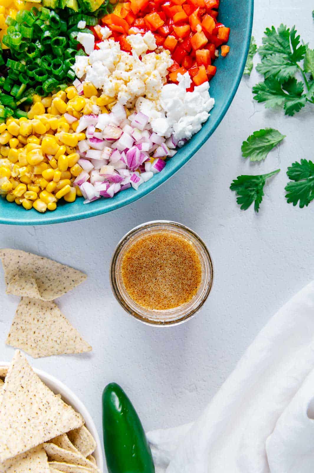 Homemade Dressing for Cowboy Caviar next to a bowl of cowboy caviar ingredients in a blue bowl.