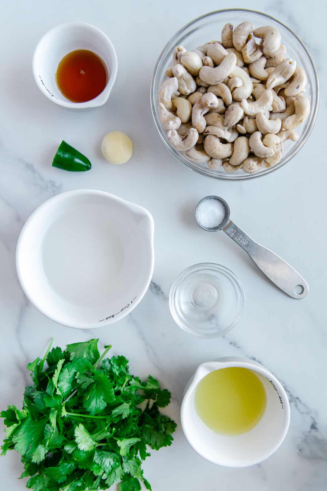 Cilantro lime sauce ingredients in separate bowls with marble white background.