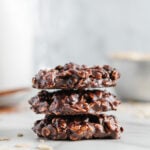 Three chocolate no-bake vegan cookies stacked on top of each other.
