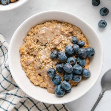 Quinoa breakfast bowl topped with almond butter and blueberries.