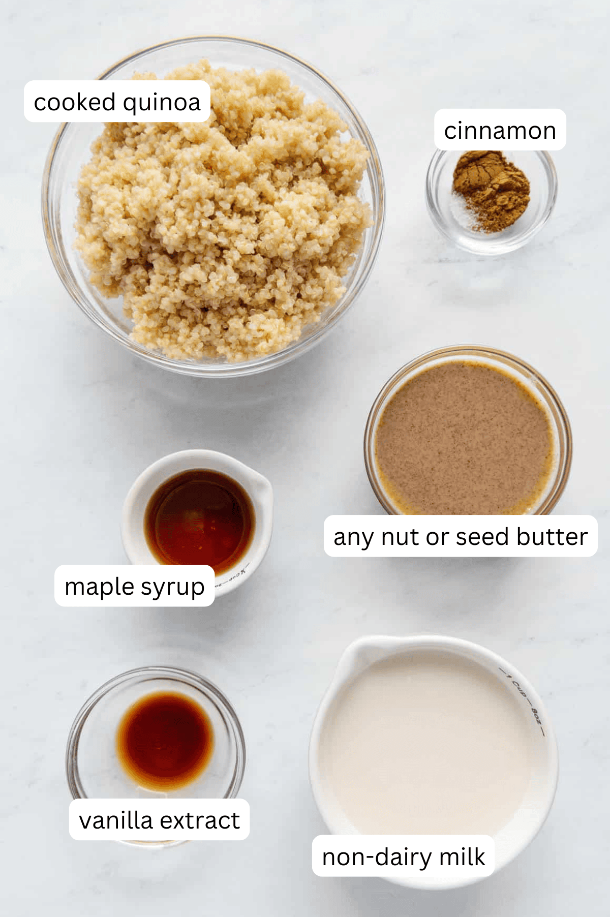 Ingredients of a quinoa breakfast bowl in separate bowls with a white background.