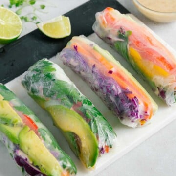 Vegan summer rolls on a white platter served with a tahini-based sauce.
