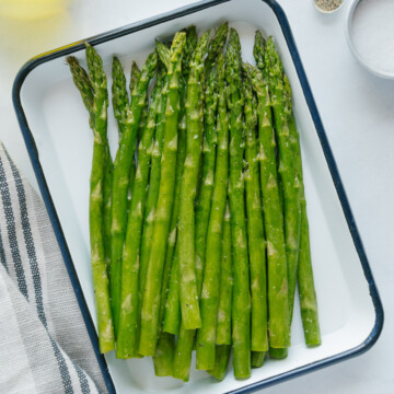 Air fryer asparagus on a white platter with a blue rim.