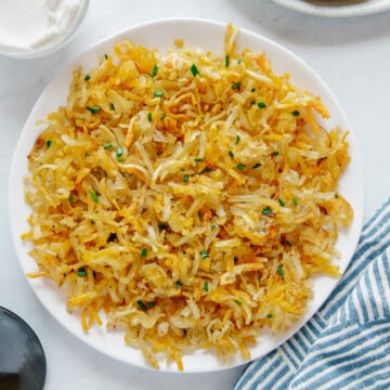 Air fryer hash browns on a white plate with a white background.