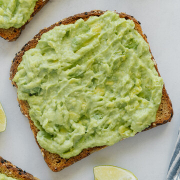 Avocado spread on a piece of toast with a white background.