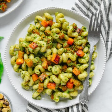Pesto Pasta with Maple Roasted Butternut Squash on a white plate with a silver fork.