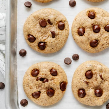 Oat flour chocolate chip cookies on a lined baking sheet.