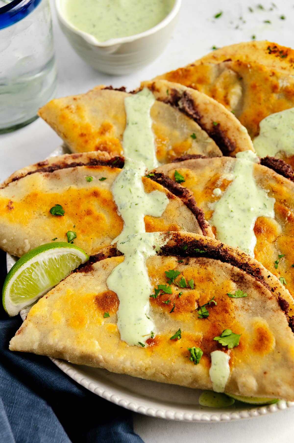 Crispy fried black bean tacos drizzled with a creamy cilantro sauce.