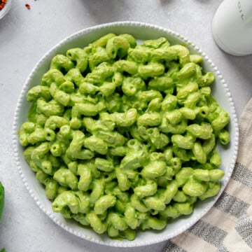Pasta with green pasta sauce in a white bowl.