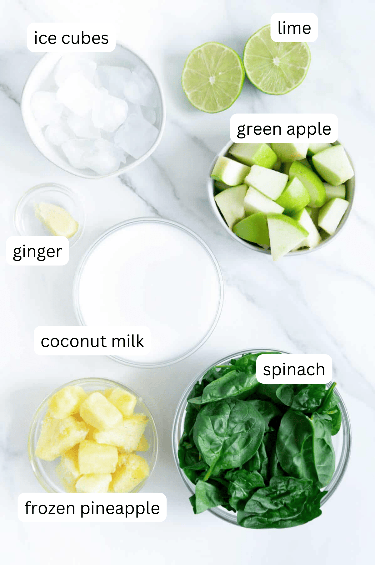 Ingredients of a green detox smoothie with a white marble background.