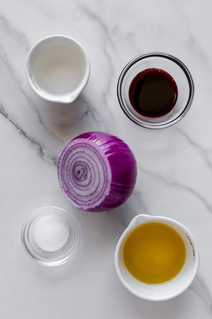 Marinated onion ingredients with a white marble background.