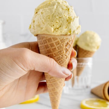 Vegan lemon ice cream being held in an ice cream cone.