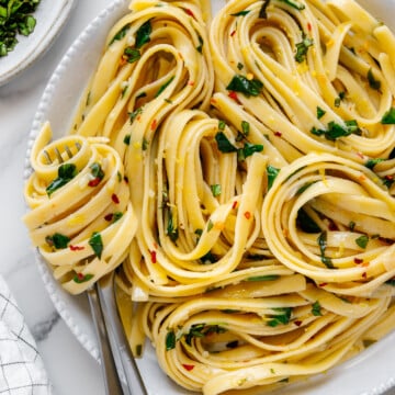 Lemon spinach pasta on a white plate served with a silver fork with a white background.