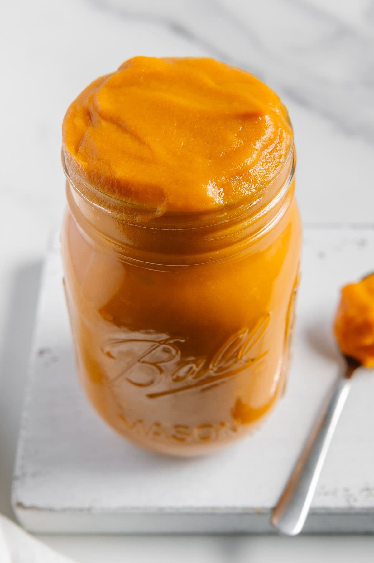 Sweet potato puree in a glass mason jar with a white background.