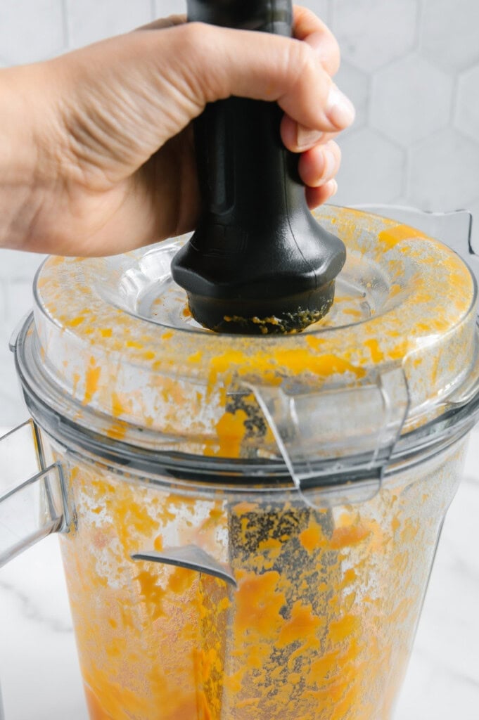 Using a tamper for sweet potato puree in a blender.