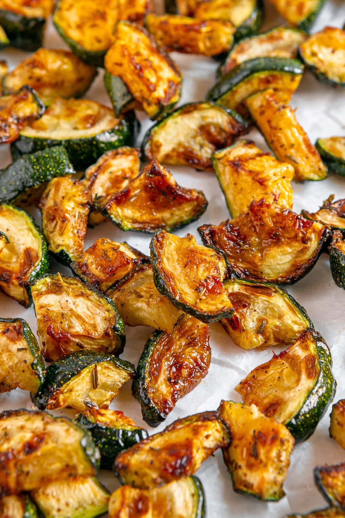 Air fryer zucchini pieces on white parchment paper.