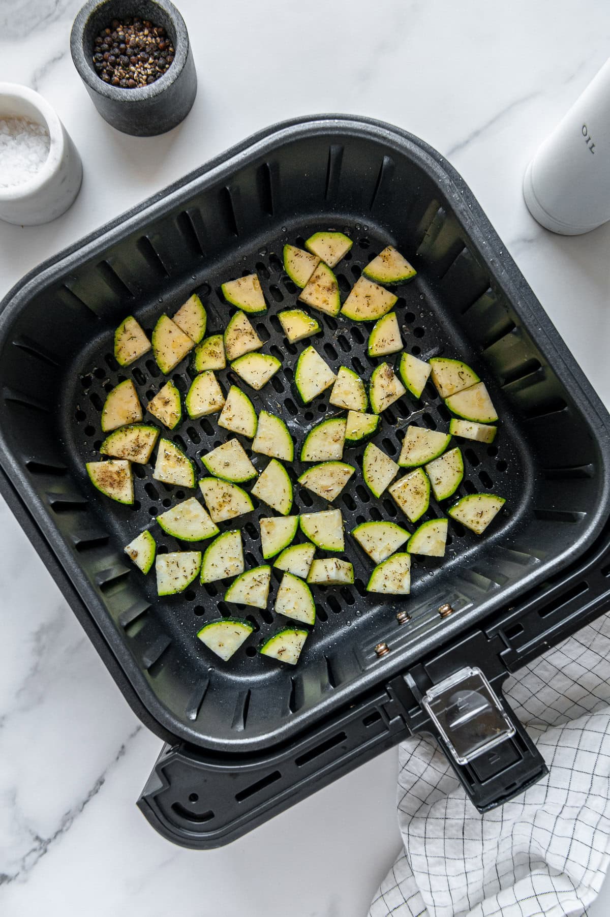 Diced zucchini in a black air fryer basket.