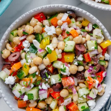 Mediterranean dense bean salad in a white bowl with a white marble background.