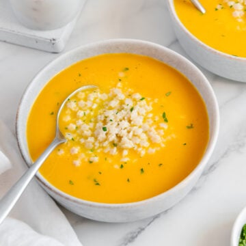 Italian penicillin soup in two white bowls served with spoons on a white marble background.