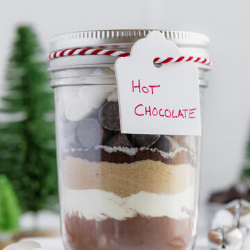 Hot chocolate in a mason jar with a pink and white ribbon around the lid securing a label for hot chocolate.