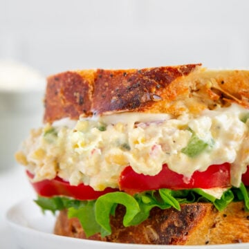 Vegan Chickpea Salad sandwich with lettuce and tomato on white background.