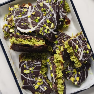 Dubai chocolate date bark broken into large pieces served on a white rectangular platter with a blue rim with a white background.
