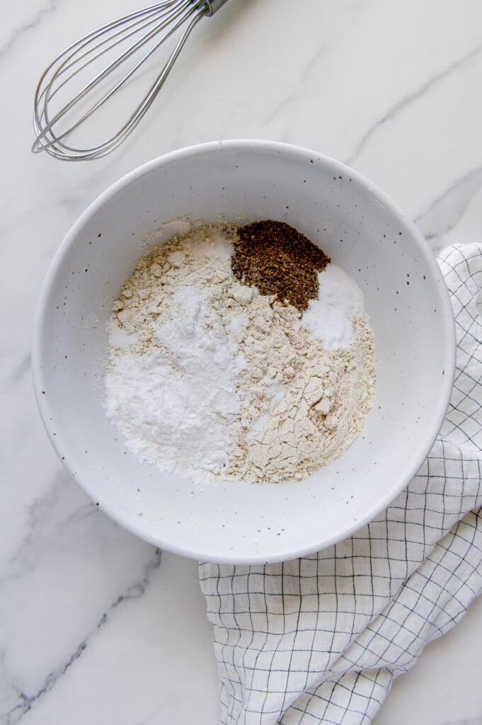 Dry ingredients for vegan blueberry muffins in a white mixing bowl.