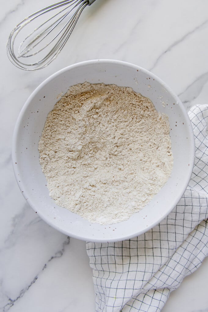 Dry ingredients for vegan blueberry muffins mixed together in a white mixing bowl.