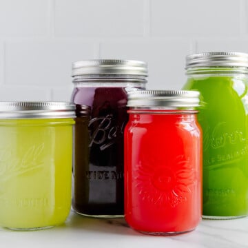 Four flavors of homemade nature's gatorade in mason jars with a white background.