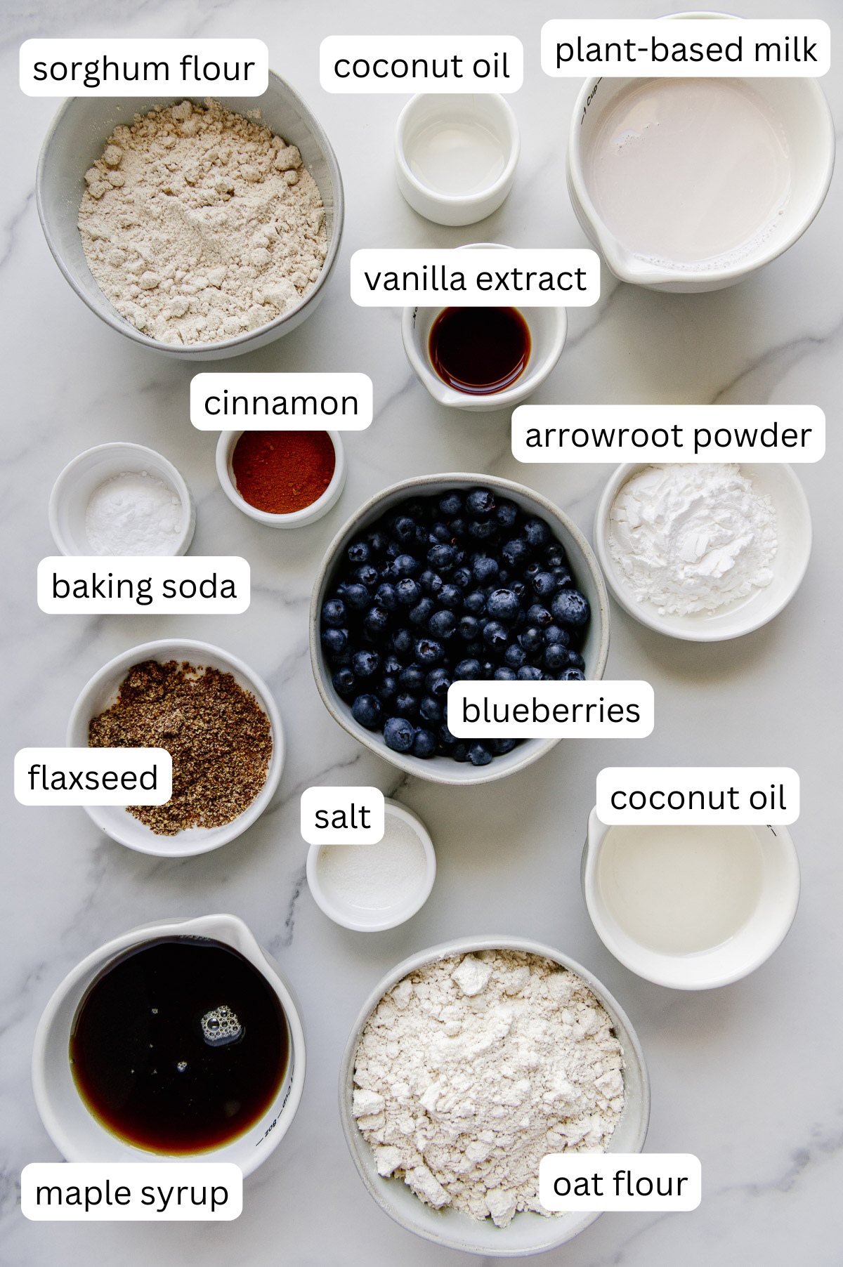 Ingredients of vegan blueberry muffins made with sorghum flour with a white marble background.