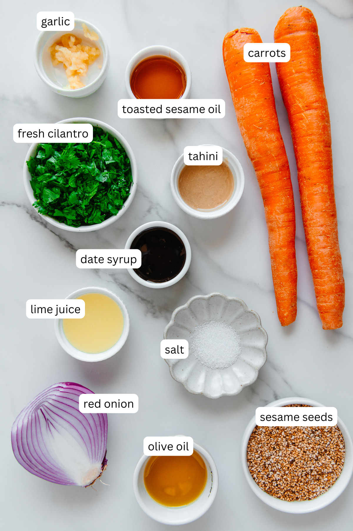 Carrot ribbon salad ingredients with a white marble background.