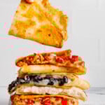 A stack of vegan quesadillas with various fillings in each with a white background.