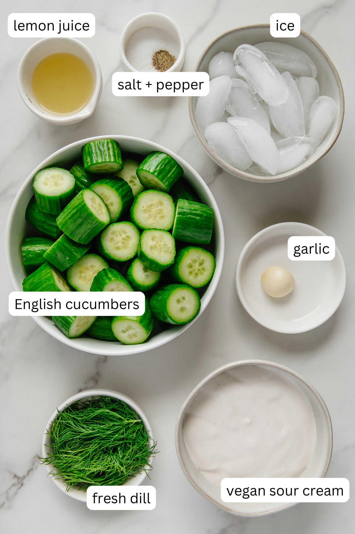 Ingredients for creamy vegan cucumber soup with a white marble background.