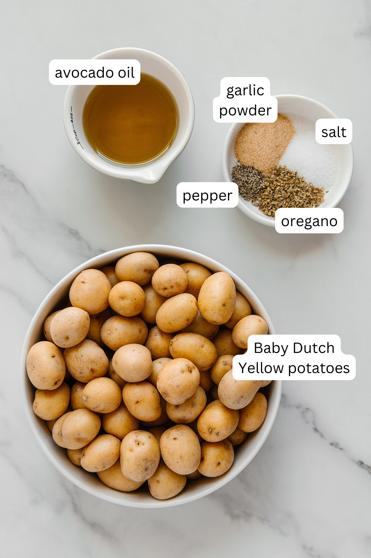 Ingredients for crispy roasted potatoes with a white marble background.