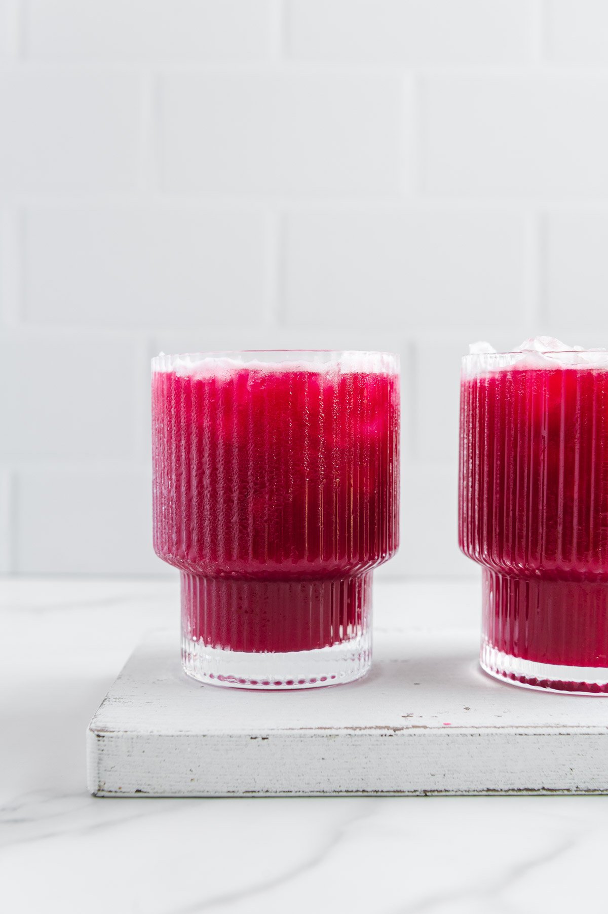Two glasses of homemade fruit punch on a white board with a white background.
