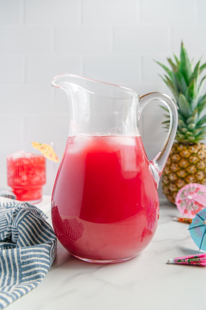 Hawaiian punch made with real fruit in a glass pitcher with a white background.