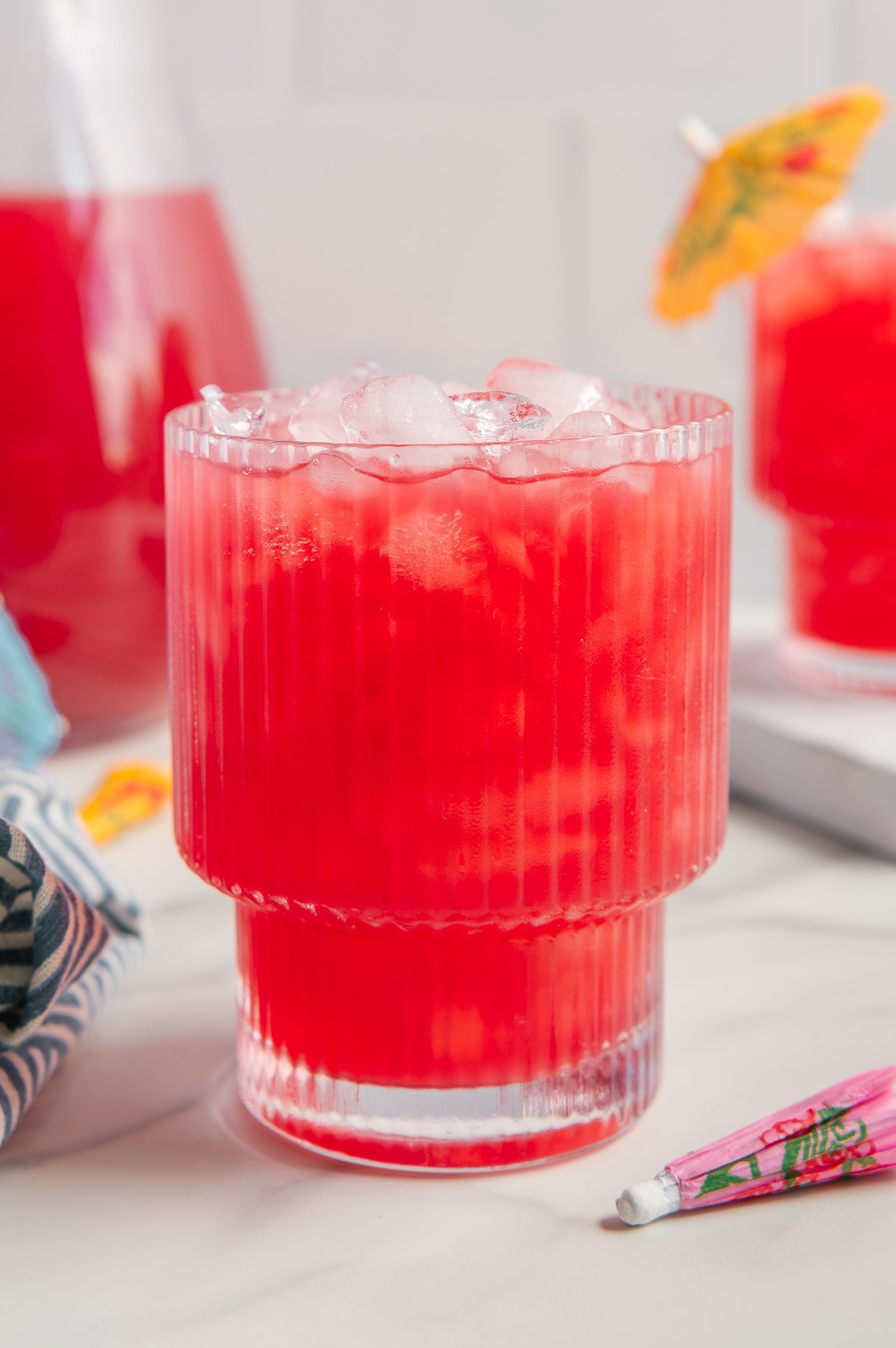 Hawaiian punch in a glass with ice with a white marble background.