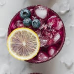 Fresh blueberry lemonade garnished with a lemon slice and fresh blueberries.