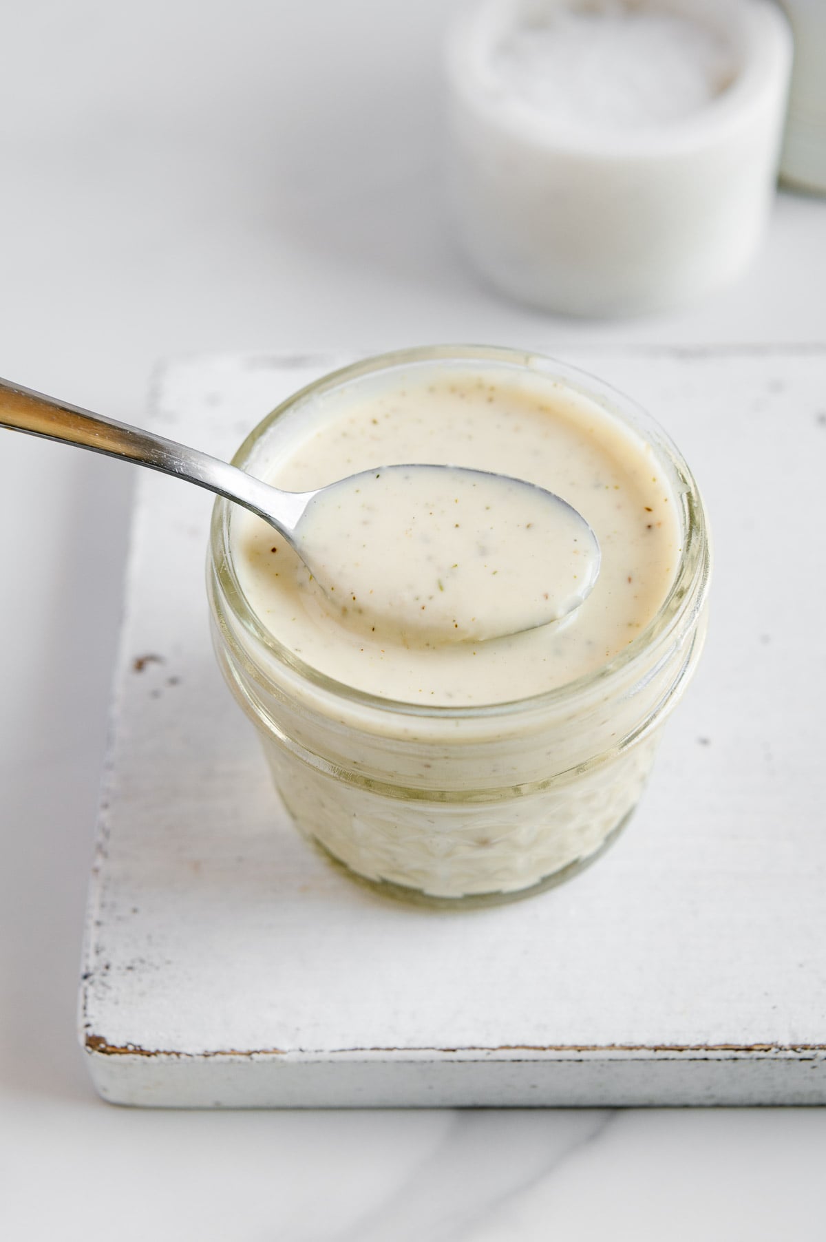 Vegan Italian dressing in a small glass jar with a white background.